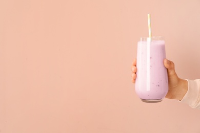 Woman holding fig smoothie on pink background, closeup. Space for text