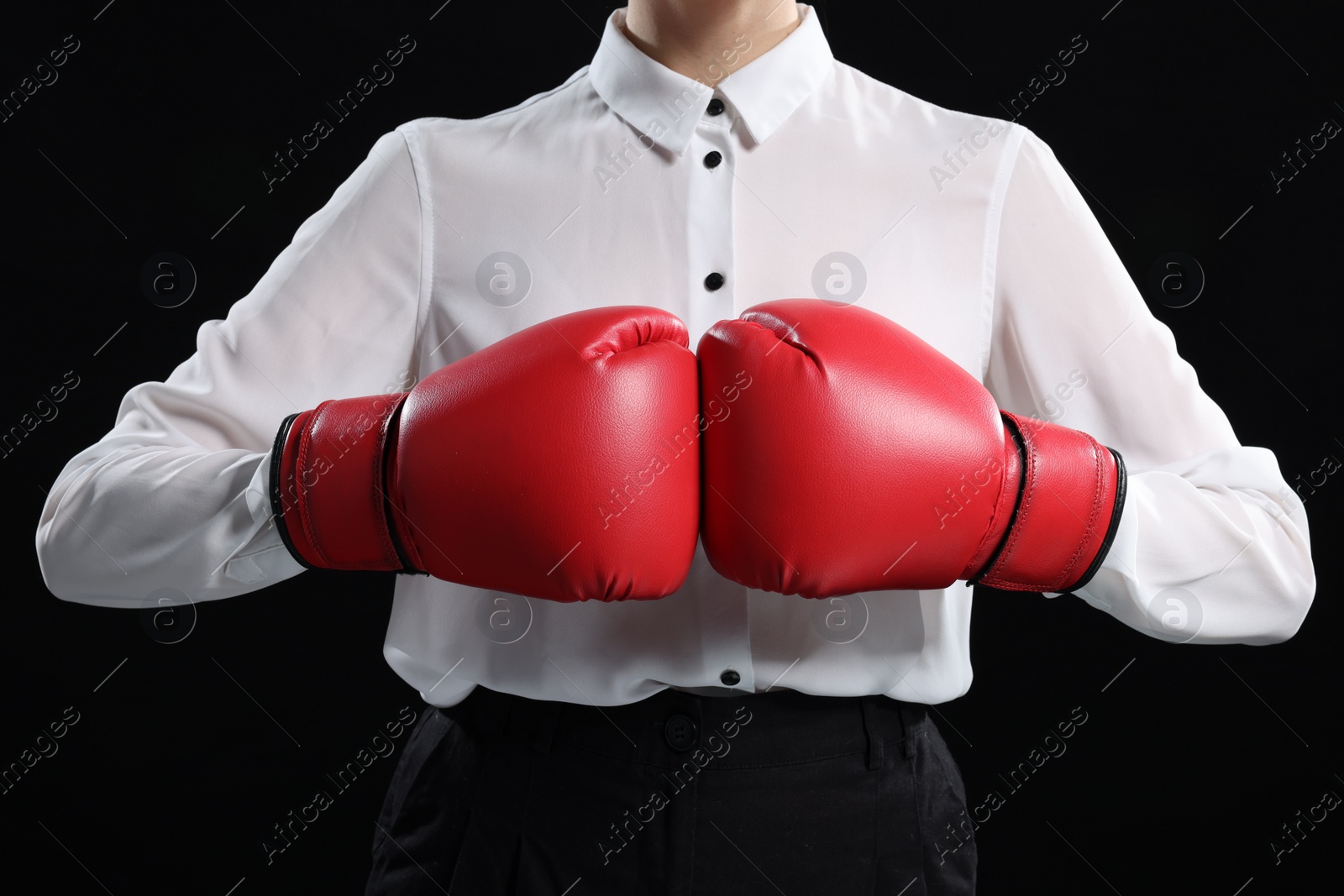 Photo of Businesswoman in shirt wearing boxing gloves on black background, closeup