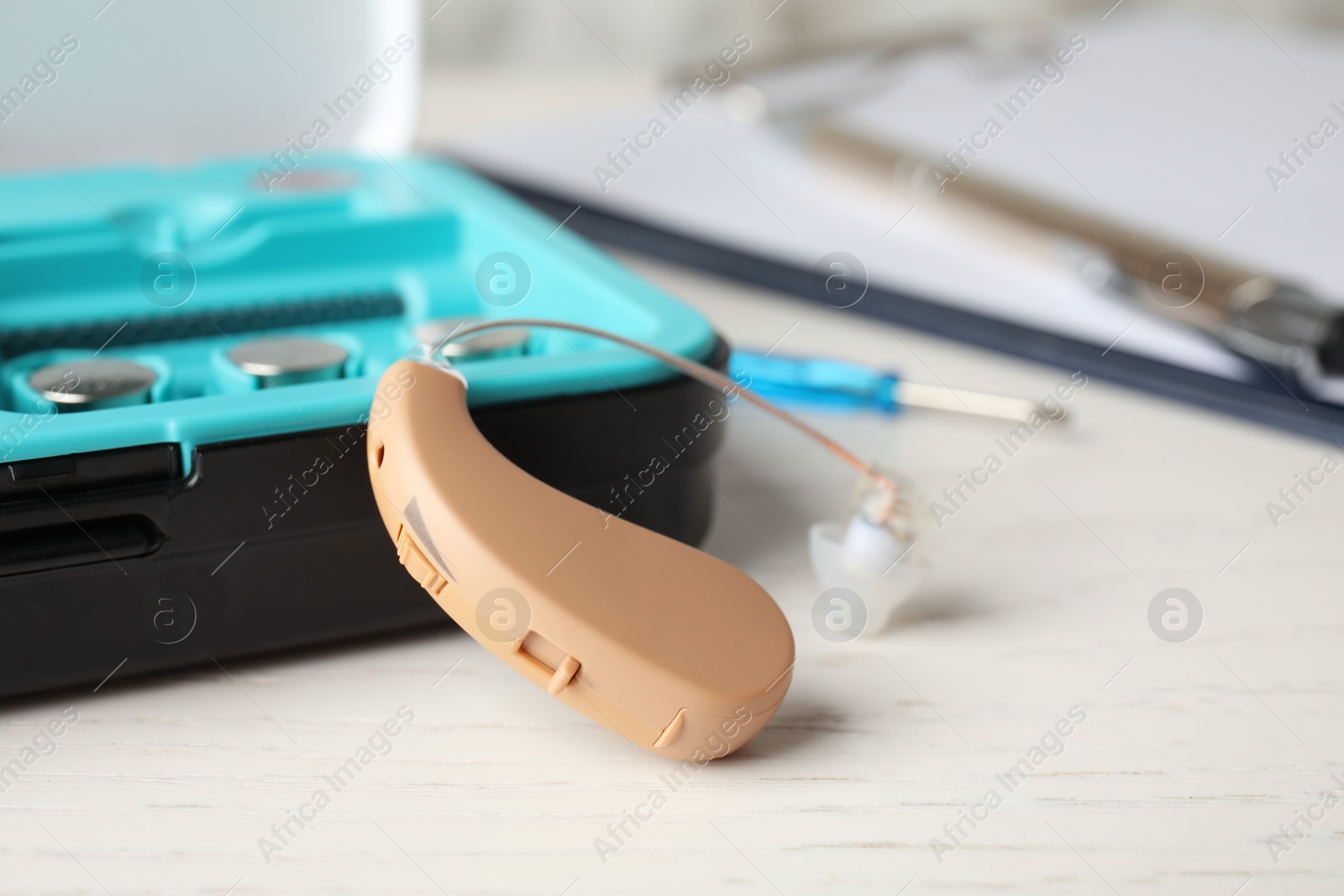 Photo of Hearing aid and case on white table, closeup