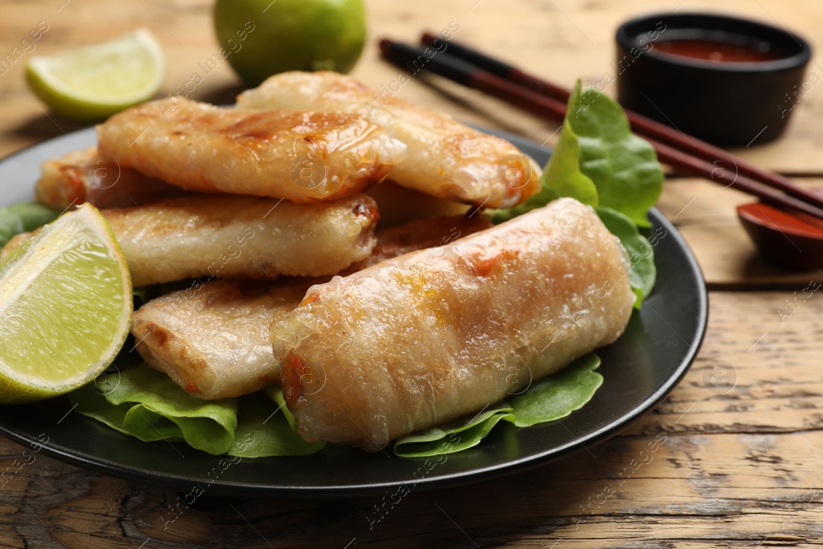 Photo of Tasty fried spring rolls served on wooden table, closeup