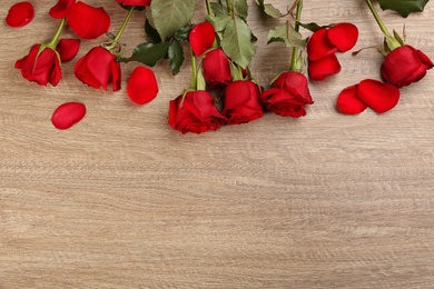 Beautiful red roses and space for text on wooden background, flat lay. Valentine's Day celebration