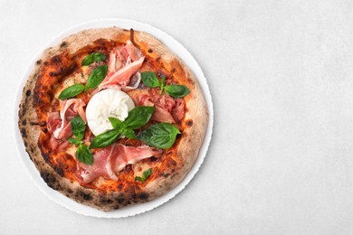 Delicious pizza with burrata cheese, basil and ham on light gray table, top view. Space for text