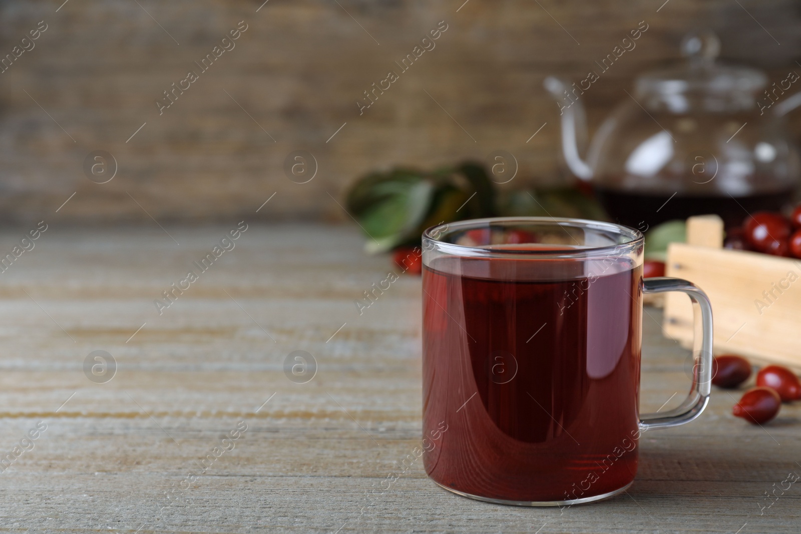 Photo of Glass cup of fresh dogwood tea on wooden table. Space for text