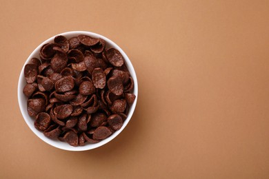 Breakfast cereal. Chocolate corn flakes in bowl on brown table, top view. Space for text