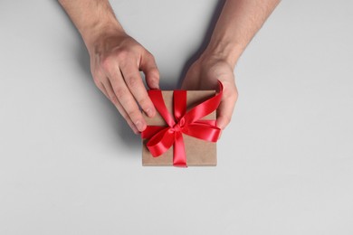 Man holding gift box with red bow on white background, top view