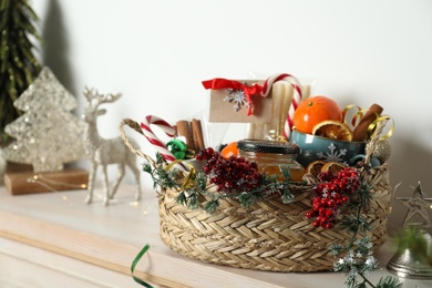 Photo of Wicker basket with gift set and Christmas decor on shelf
