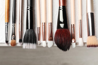 Photo of Set of different makeup brushes drying after cleaning on table, flat lay