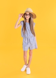 Full length portrait of cute little girl on yellow background