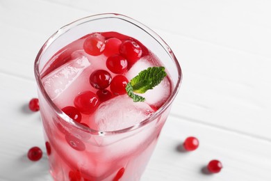 Photo of Tasty cranberry juice with ice cubes in glass on white table, closeup. Space for text