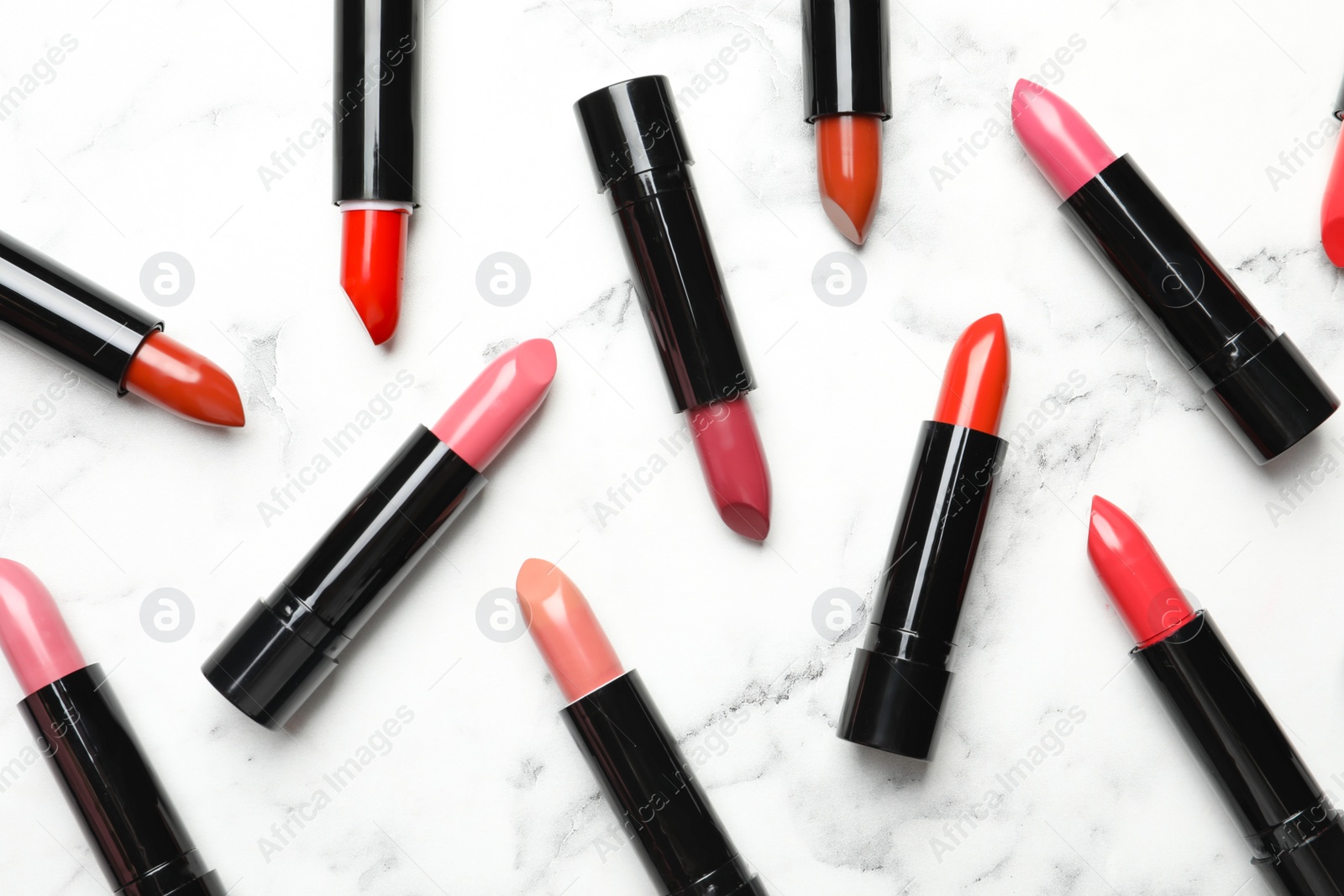 Photo of Different lipsticks on marble background, flat lay