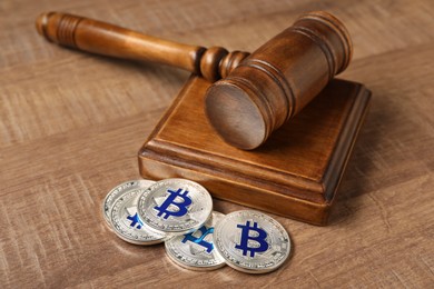 Photo of Law concept. Gavel and bitcoins on wooden table, closeup