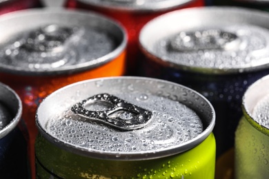 Photo of Aluminum cans of beverage covered with water drops as background, closeup