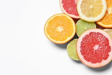 Photo of Different cut citrus fruits on white table, flat lay. Space for text