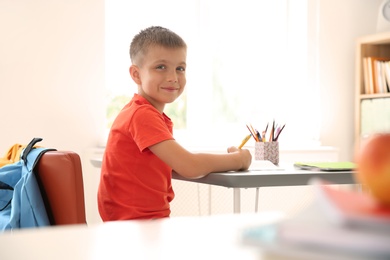 Cute little child sitting at desk in classroom. Elementary school