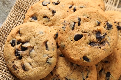 Photo of Delicious chocolate chip cookies on burlap fabric, closeup