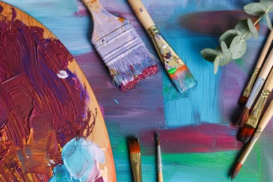 Colorful paints, wooden artist's palette and brushes, flat lay