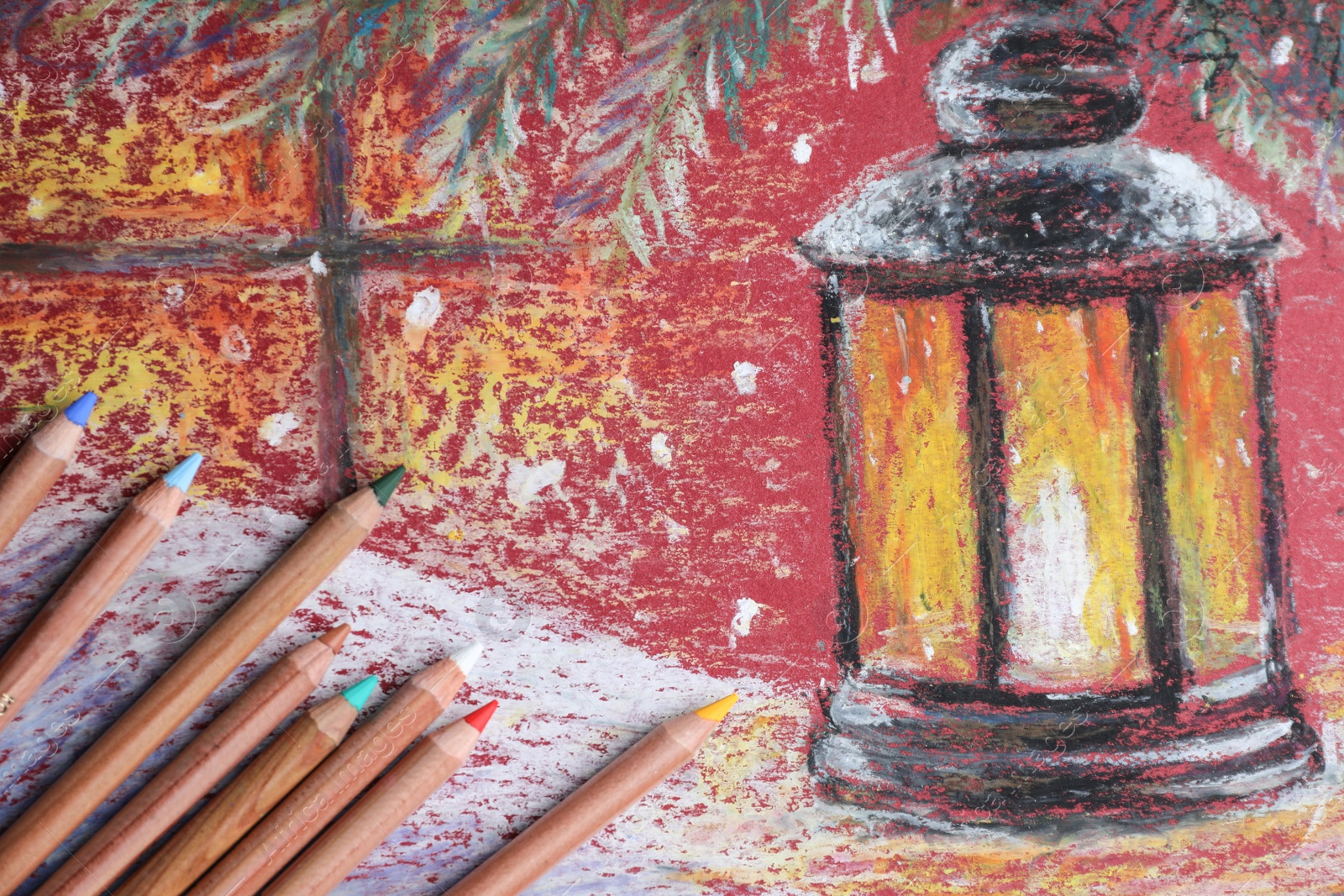 Photo of Colorful pastel pencils on beautiful painting of lantern, flat lay