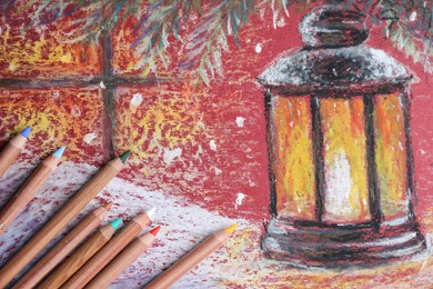 Photo of Colorful pastel pencils on beautiful painting of lantern, flat lay