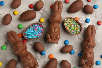 Photo of Flat lay composition with chocolate Easter bunnies, eggs and candies on light grey table
