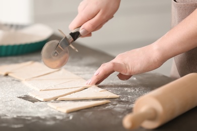 Woman preparing tasty croissants on table in kitchen, closeup