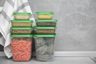 Plastic containers filled with food products on grey table. Space for text