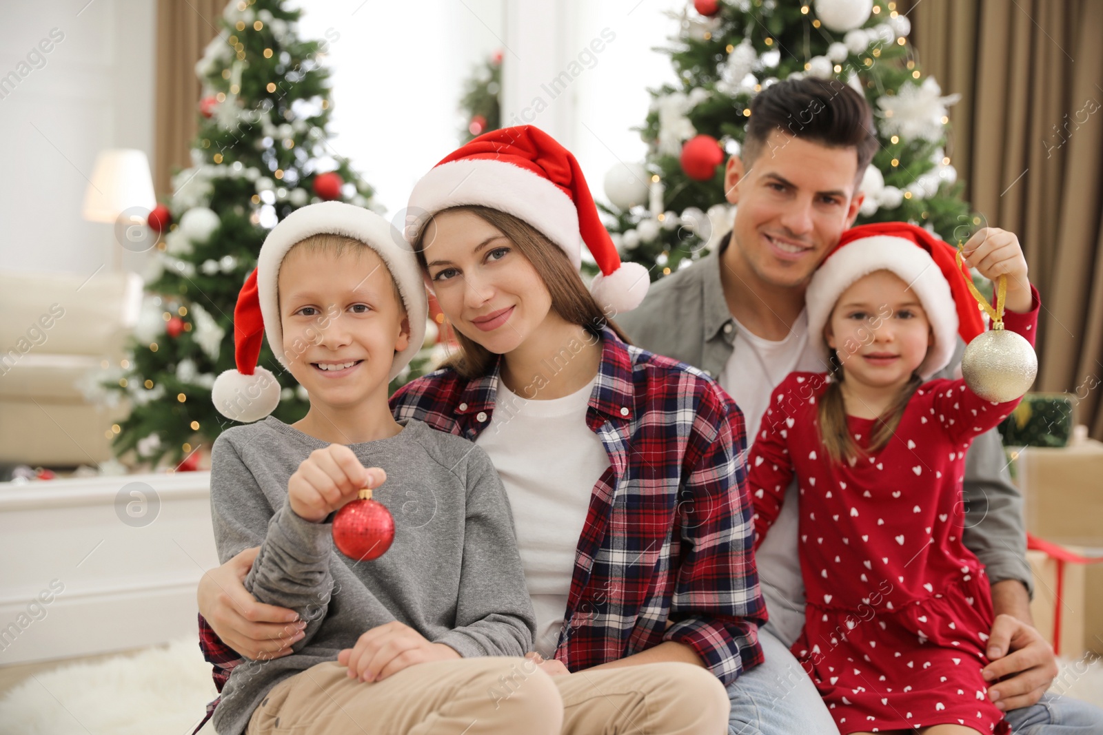 Photo of Happy family with cute children near Christmas tree together at home