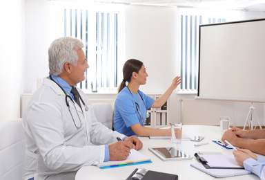 Team of doctors using video projector during conference indoors