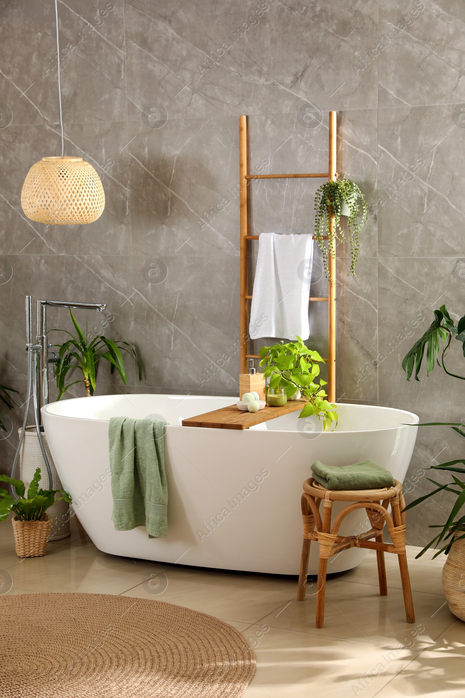 Photo of Modern white tub and beautiful green houseplants in bathroom. Interior design