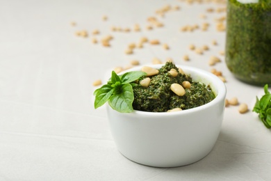 Photo of Homemade basil pesto sauce with pine tree nuts in bowl on table