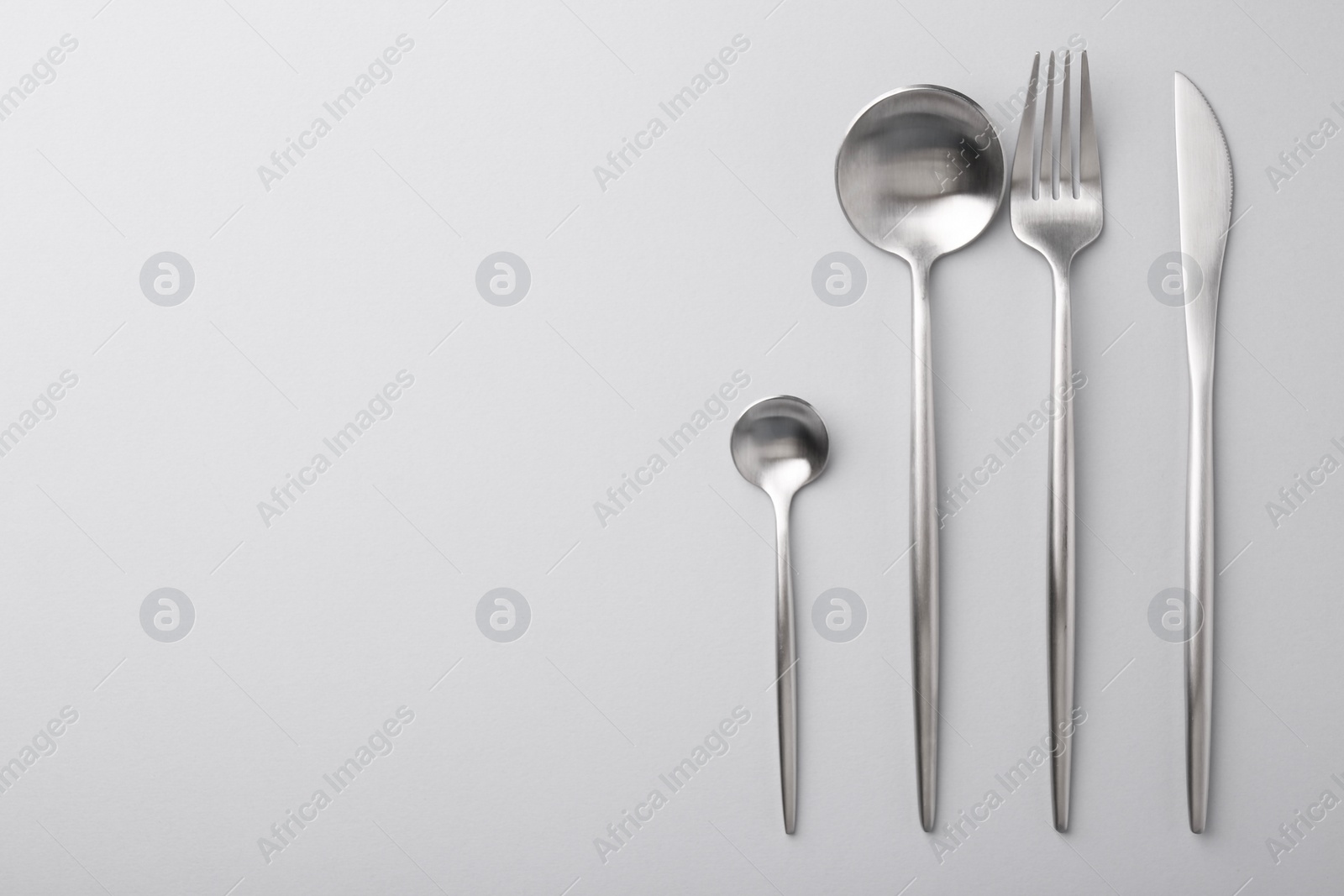 Photo of Stylish cutlery set on grey table, flat lay. Space for text