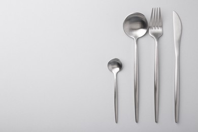 Photo of Stylish cutlery set on grey table, flat lay. Space for text