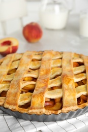 Delicious fresh peach pie on light kitchen table, closeup