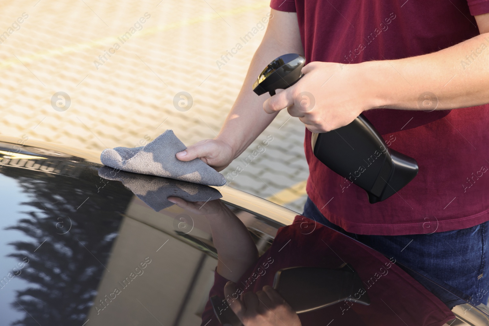 Photo of Man cleaning car hood outdoors, closeup view