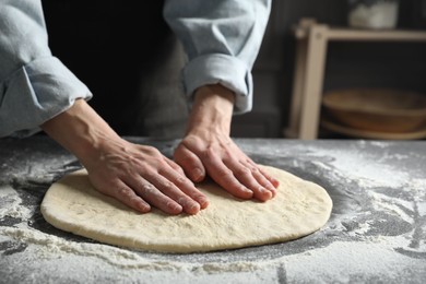 Photo of Woman making pizza dough at table, closeup