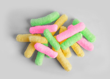 Pile of colorful corn puffs on light grey background, top view