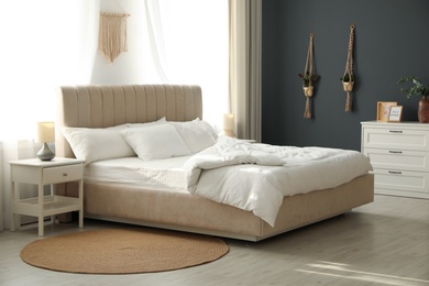 Photo of Comfortable bed with soft blanket in stylish room interior