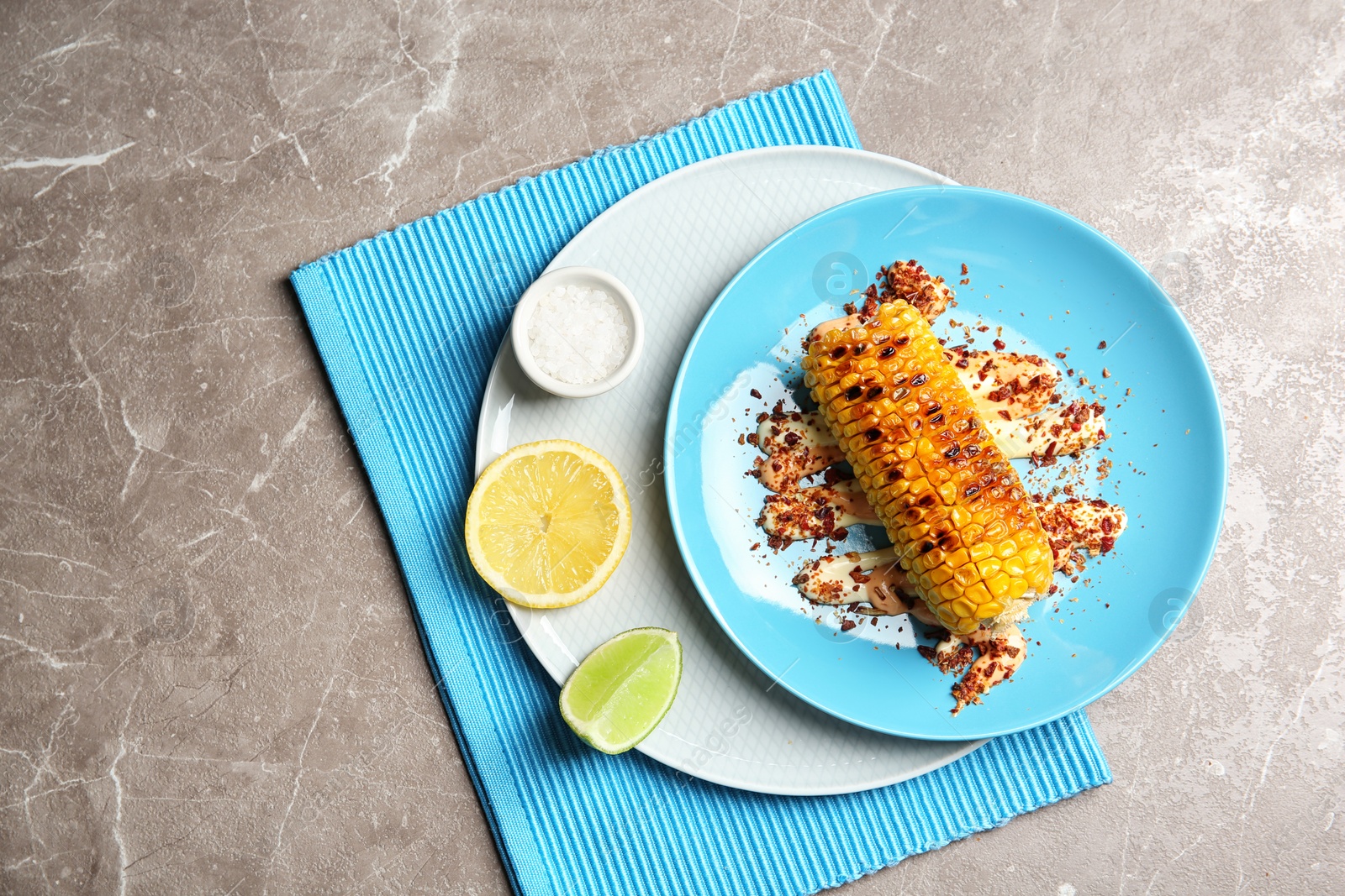 Photo of Plate with delicious grilled corn cob and spices on table, top view