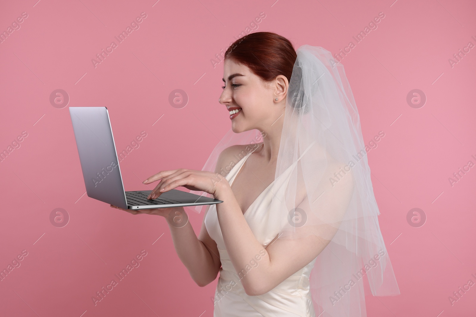 Photo of Happy bride with laptop on pink background