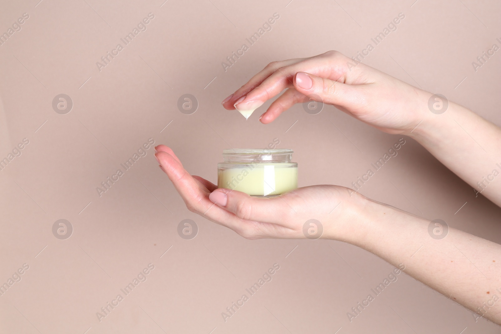 Photo of Woman with jar of cream on beige background, closeup