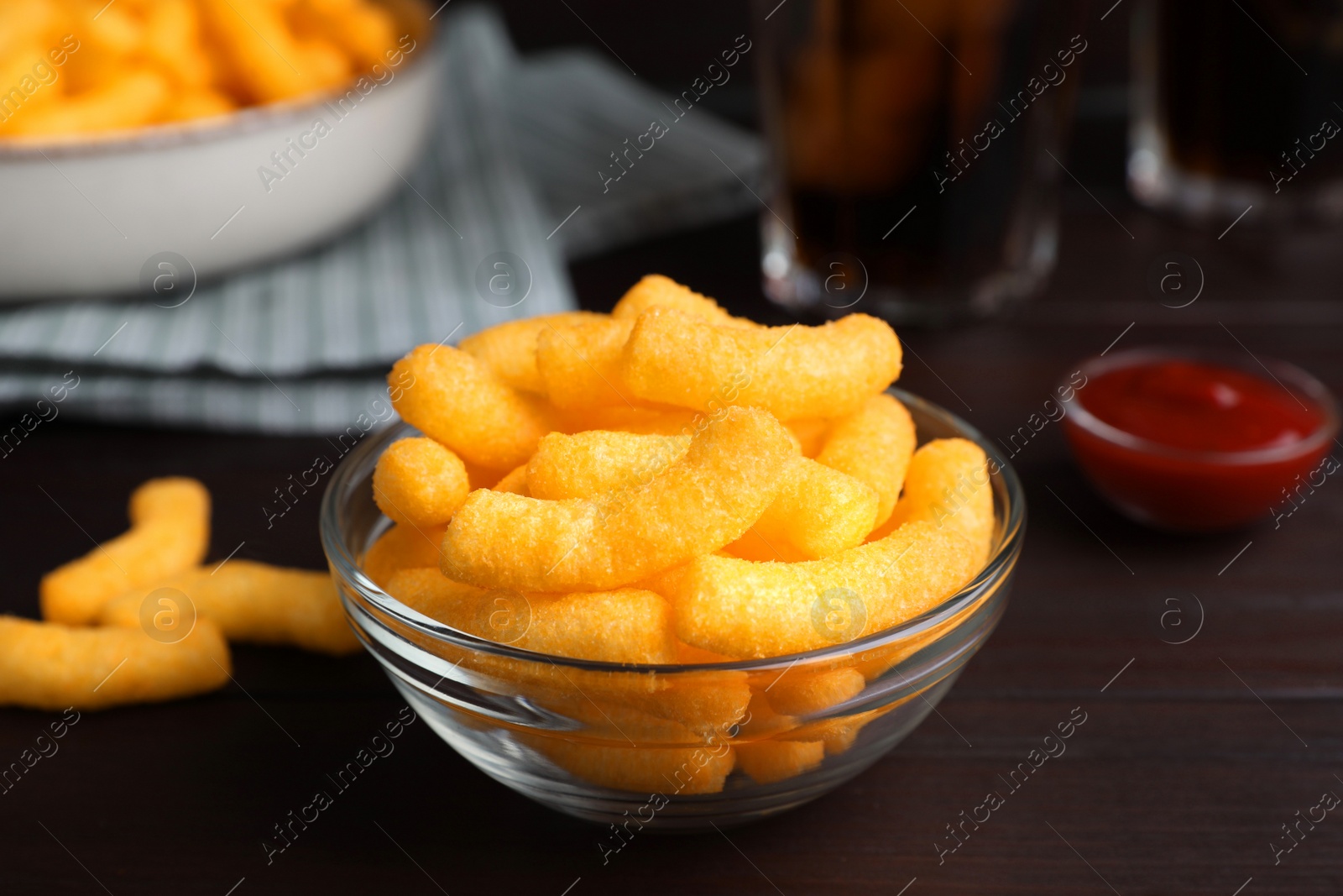 Photo of Crunchy cheesy corn snack on wooden table, closeup