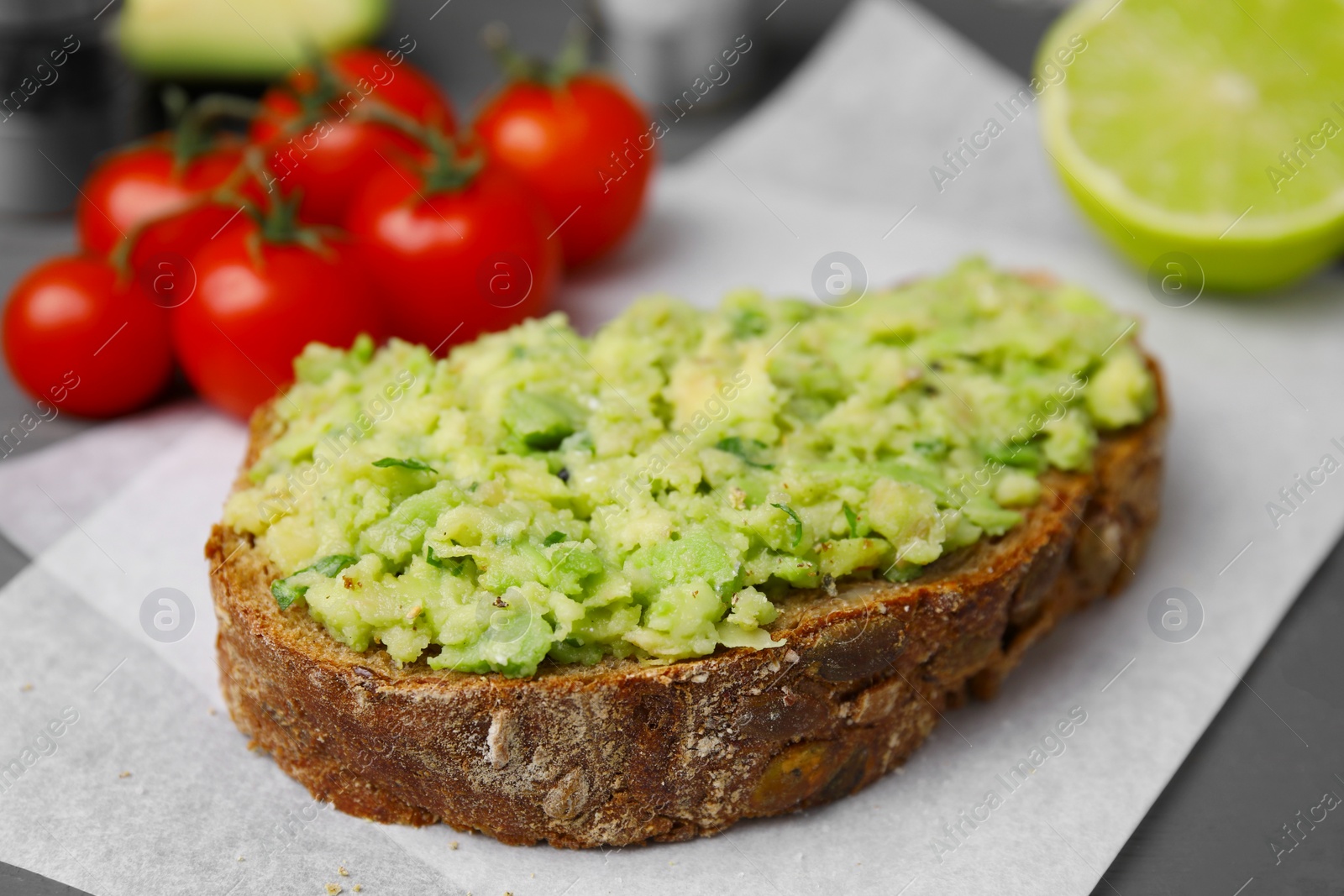 Photo of Delicious sandwich with guacamole on parchment paper, closeup