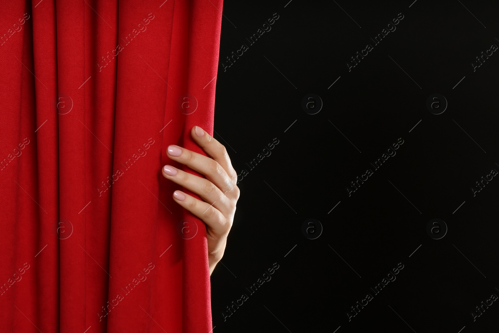 Photo of Woman opening red front curtains on black background, closeup. Space for text