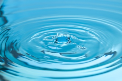 Photo of Splash of blue water with drop, closeup