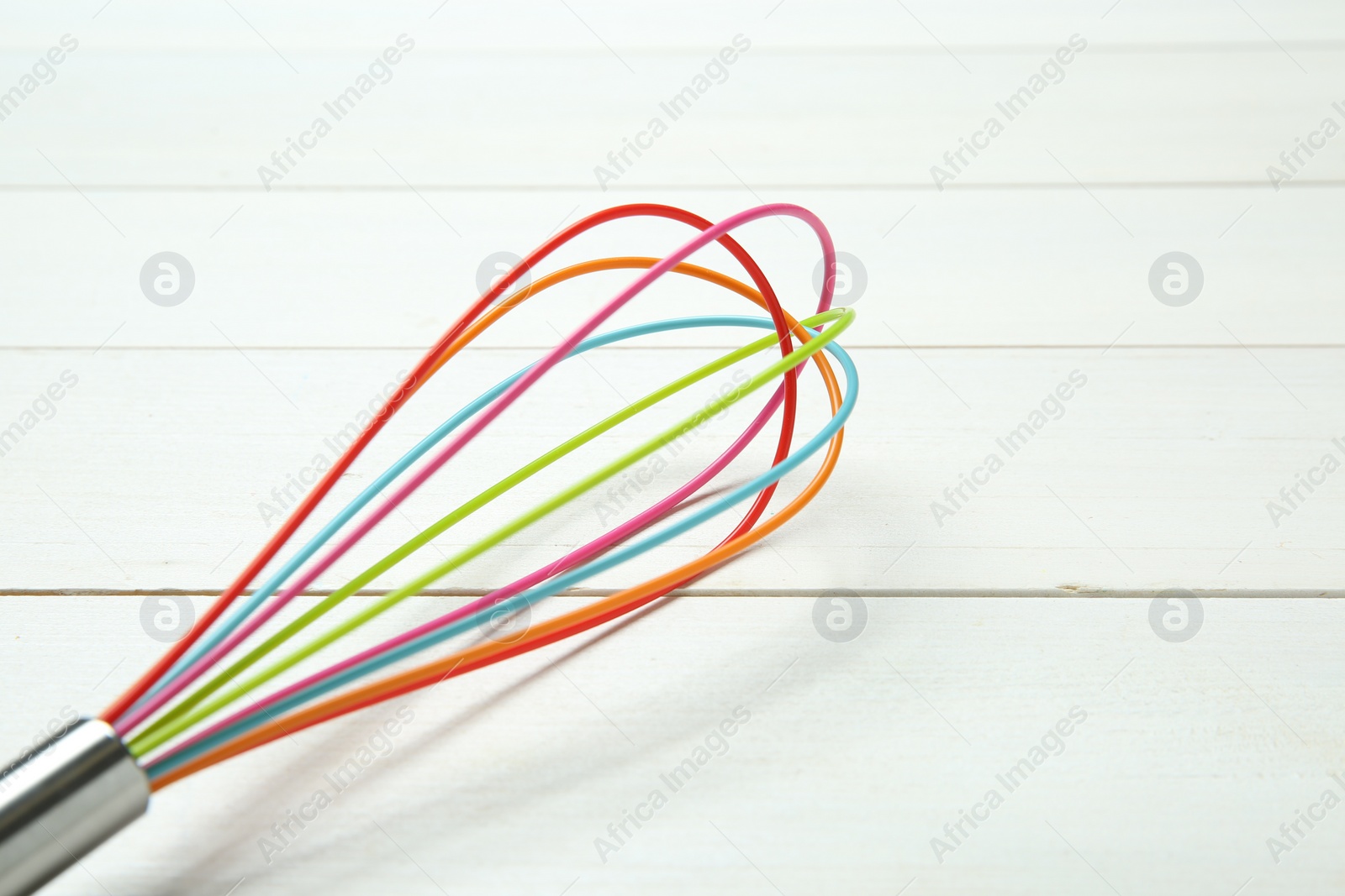 Photo of One whisk on white wooden table, closeup. Space for text