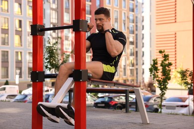 Photo of Man doing abs exercise on bench at outdoor gym