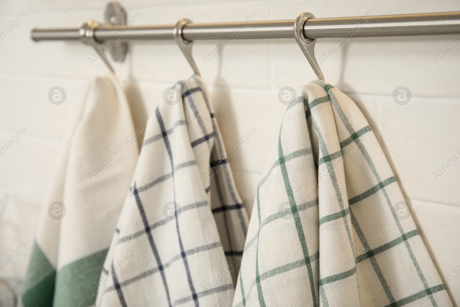 Photo of Different kitchen towels hanging on rack, closeup