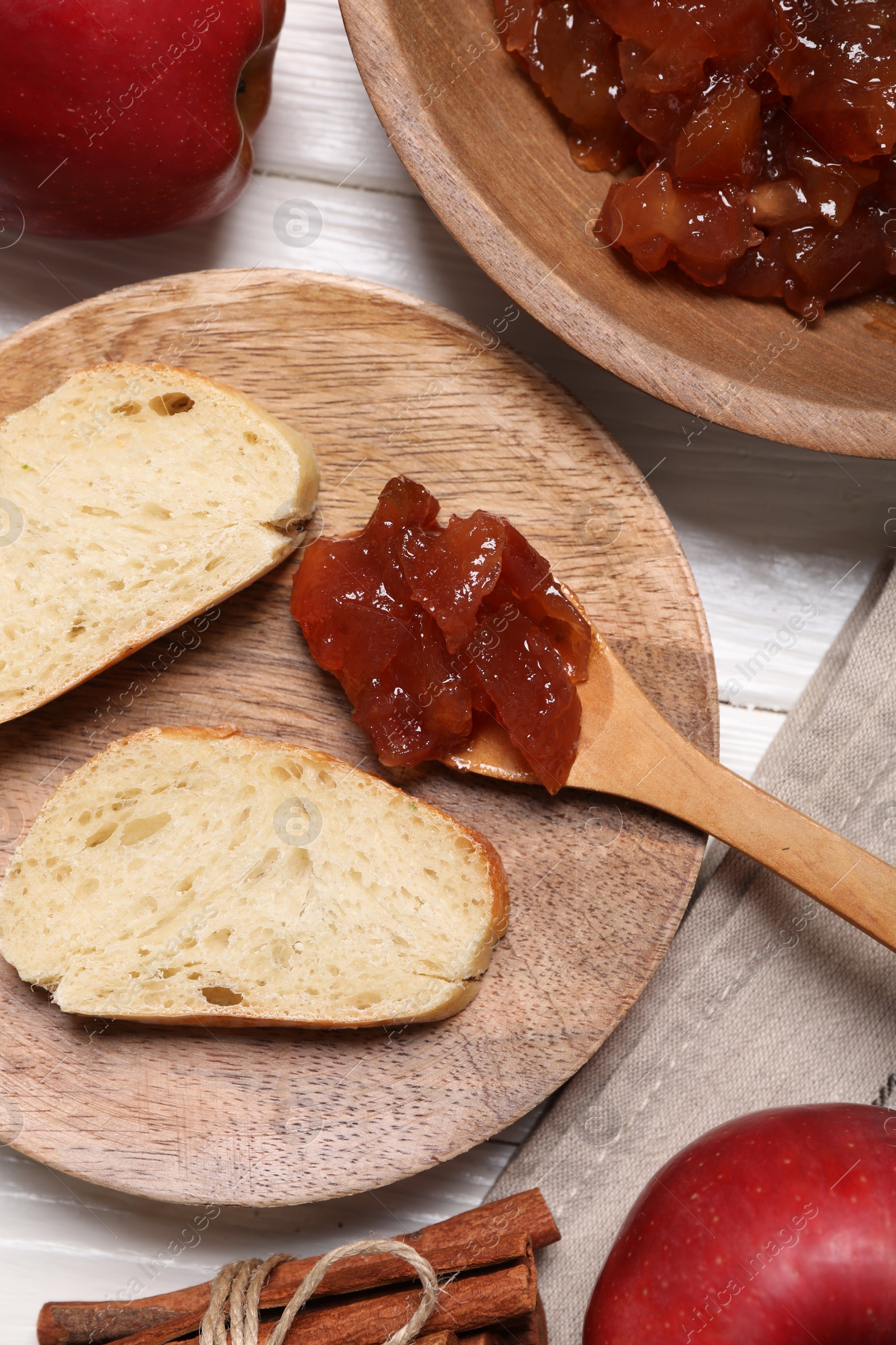 Photo of Delicious apple jam and bread slices on white wooden table, flat lay