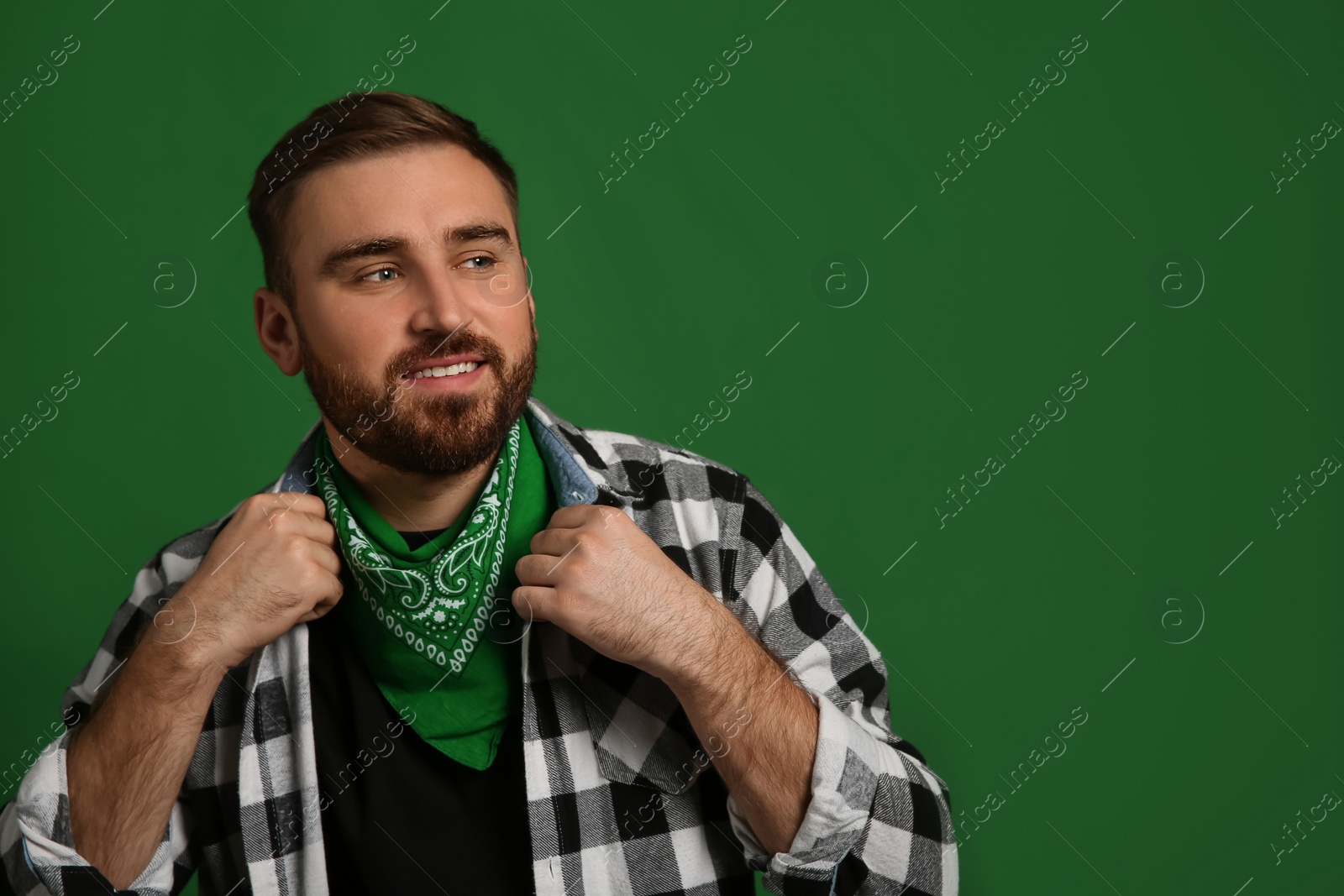 Photo of Fashionable young man in stylish outfit with bandana on green background, space for text