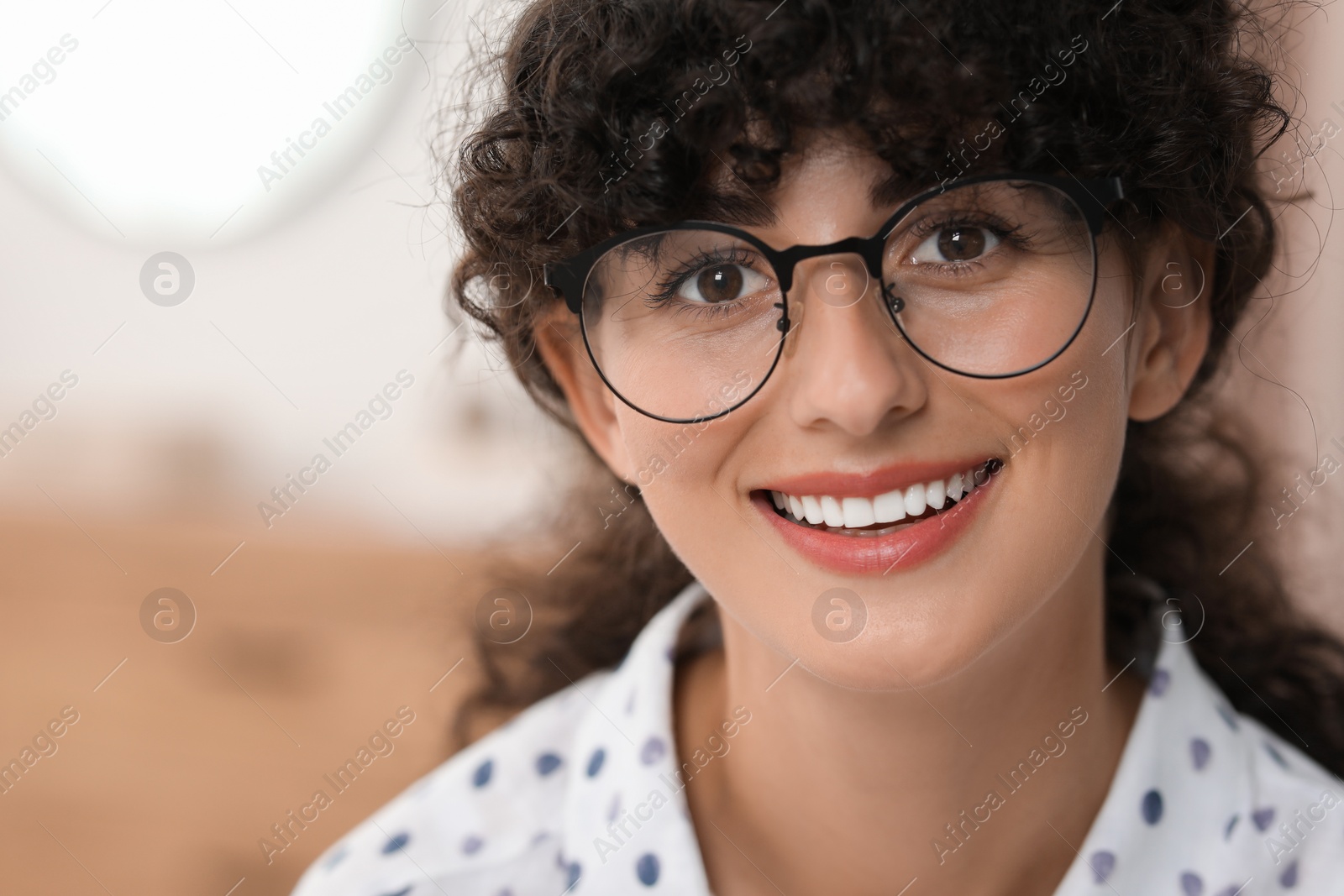 Photo of Portrait of beautiful woman with curly hair on blurred background. Attractive lady smiling and looking into camera. Space for text