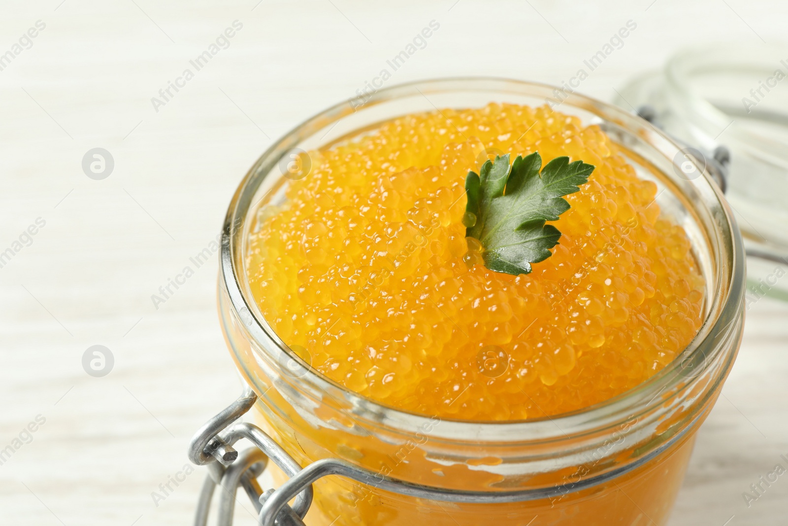 Photo of Fresh pike caviar and parsley in glass jar on table, closeup